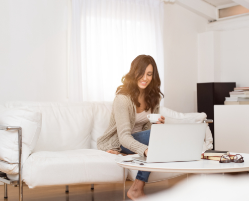 woman using her laptop holding a cup