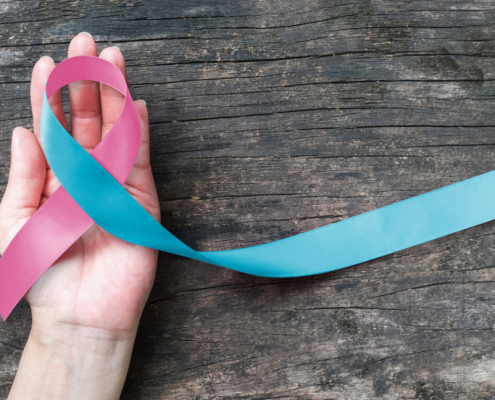 Hand holding a pink ribbon for pregnancy loss awareness