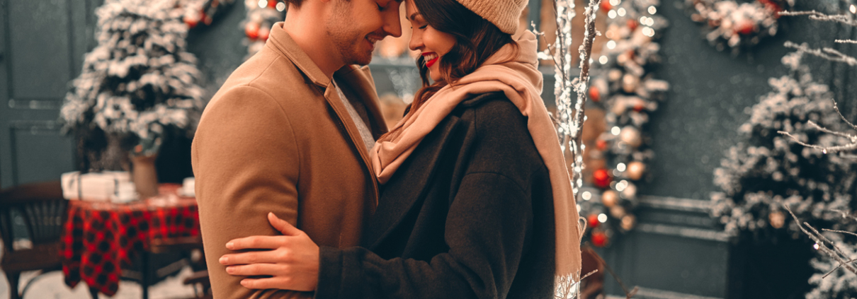 Young romantic couple is having fun outdoors in winter before Christmas. Enjoying spending time together in New Year Eve. Two lovers are hugging and kissing in Saint Valentine's Day.