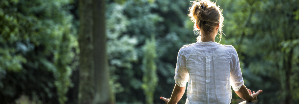 Young blonde woman meditating in the park