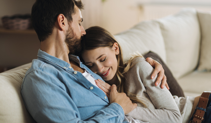 Young affectionate couple enjoying together while man is kissing his girlfriend in head