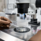 A specialist in brown latex gloves checks on eggs from egg retrieval in a petri dish.