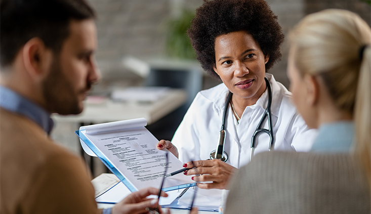 Female doctor talking to a couple in an office about the egg retrieval process.