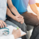 Couple holding hands and sitting together while consulting with a fertility treatment specialist in a medical setting.