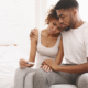 Black couple sitting together looking disappointed while holding a negative pregnancy test