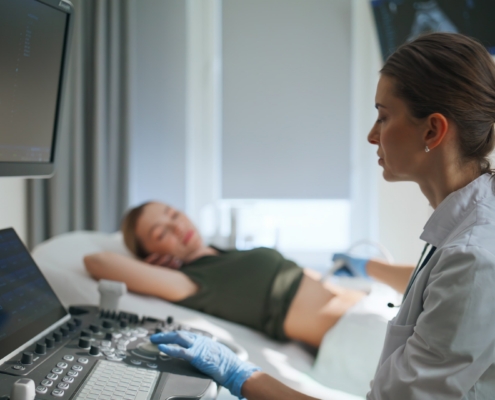 Healthcare professional performing ultrasound examination on pregnant patient's abdomen in medical clinic