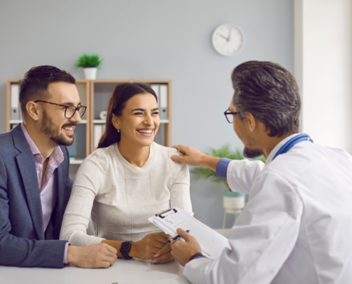 Doctor at desk consulting with young couple about pregnancy planning and fertility treatment options