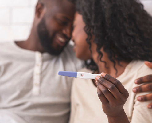 Couple holding positive pregnancy test together.