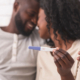 Couple holding positive pregnancy test together.