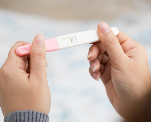 Woman holding and viewing a negative pregnancy test.