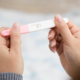 Woman holding and viewing a negative pregnancy test.